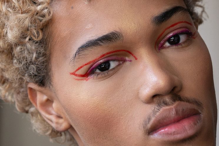 An ethnic man in red eyeliner and face makeup